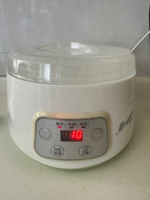 预备一个做乳酪的容器，将牛奶与一小杯酵母倒进玻璃容器里调匀，玻璃容器的外面加少许开水平口，盖上盖子插电调节保温状态10小时