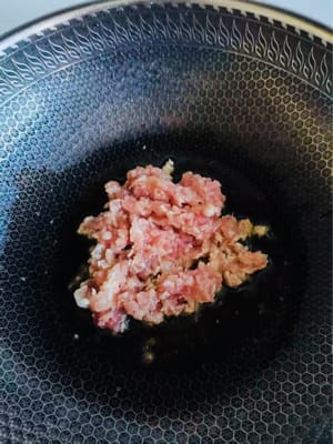Calentar la sartén, agregar aceite y verter la carne cortada en cubitos en el aceite caliente.