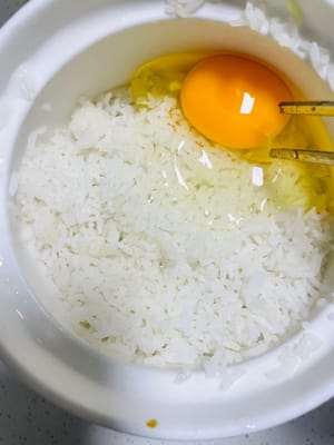 處理冷飯：將冷飯加入一小匙冷水抓散。若需為炒飯增香提色，可打入一顆蛋抓均勻；若不喜蛋或有其他飲食需求，可直接進行後續炒飯步驟，忽略此加蛋操作。