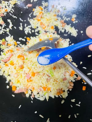 熱鍋放油（推薦使用豬油，可增添炒飯香氣；無豬油時，食用油也可 ），將冷飯倒入鍋中，炒至米飯粒粒分明。接著加入之前炒好的芹菜、紅蘿蔔等配菜，翻炒均勻，再加入1小匙生抽、鹽、少量白糖（提鮮並綜合鹹味）調味，（注意培根腸仔已有鹹味，不要放鹹了）