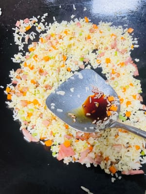 熱鍋放油（推薦使用豬油，可增添炒飯香氣；無豬油時，食用油也可 ），將冷飯倒入鍋中，炒至米飯粒粒分明。接著加入之前炒好的芹菜、紅蘿蔔等配菜，翻炒均勻，再加入1小匙生抽、鹽、少量白糖（提鮮並綜合鹹味）調味，（注意培根腸仔已有鹹味，不要放鹹了）