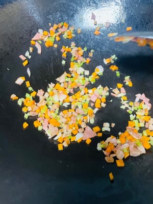 鍋中加少許油，放入洋蔥、芹菜、培根、胡蘿蔔粒，翻炒至香氣溢出、水分炒乾，撈出備用。若冷飯處理時未加蛋，可在炒香配菜後，直接倒入冷飯一同炒製。