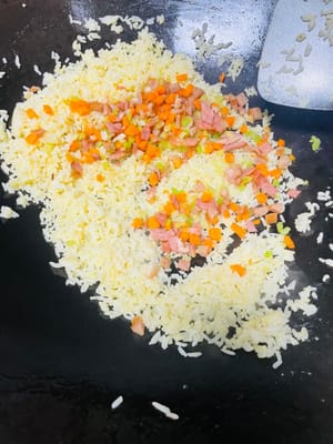 熱鍋放油（推薦使用豬油，可增添炒飯香氣；無豬油時，食用油也可 ），將冷飯倒入鍋中，炒至米飯粒粒分明。接著加入之前炒好的芹菜、紅蘿蔔等配菜，翻炒均勻，再加入1小匙生抽、鹽、少量白糖（提鮮並綜合鹹味）調味，（注意培根腸仔已有鹹味，不要放鹹了）