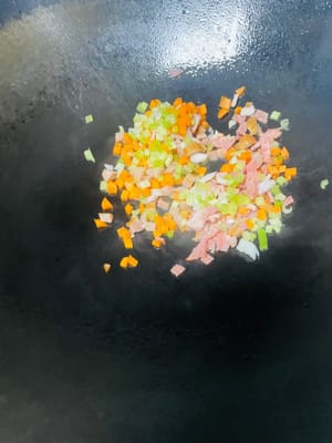 鍋中加少許油，放入洋蔥、芹菜、培根、胡蘿蔔粒，翻炒至香氣溢出、水分炒乾，撈出備用。若冷飯處理時未加蛋，可在炒香配菜後，直接倒入冷飯一同炒製。