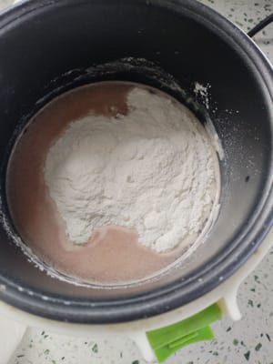 然后把水果汁倒入电饭煲，加入两勺白糖，糯米粉300克，一起边煮边搅拌。