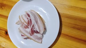 Tagliare la pancetta di maiale a fette sottili e grandi, lunghe 11 cm e larghe 3-4 cm