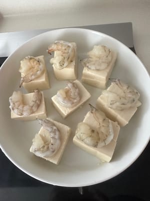 Sgusciare i gamberi e dividere il dorso a metà, quindi adagiarli sul tofu