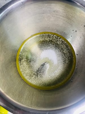 Bereiten Sie den Teig vor. Geben Sie 20 g weißen Zucker, 45 g Maisöl und 45 g Milch in eine Schüssel mit Eigelb und verquirlen Sie die Zutaten, bis eine homogene Emulsion ohne sichtbare Öltropfen entsteht.