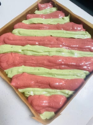 Heizen Sie den Backofen mindestens 10 Minuten lang auf 150 °C (300 °F) vor. Legen Sie eine 28 x 28 cm große Backform mit Backpapier aus.

Hinweis: Jetzt ist Ihr Geschick beim Spritzen von geraden Linien gefragt! Die Größe der Spritzbeutelöffnung und der Druck beim Aufspritzen des Teigs müssen für beide Farben gleich sein, sonst werden die Streifen krumm und bilden ein „S“! Schneiden Sie in jeden Spritzbeutel eine kleine Öffnung und spritzen Sie abwechselnd roten Hefereis- und Matcha-Teig in die Backform, um weihnachtliche Streifen zu gestalten (siehe Abbildung).

Heben Sie die Backform nach dem Aufspritzen an und lassen Sie sie zweimal vorsichtig aus etwa 10 cm Höhe fallen, um die Oberfläche zu glätten (es ist in Ordnung, wenn sich die Farben vermischen). Entfernen Sie größere Luftblasen und backen Sie den Kuchen anschließend 20 Minuten lang auf der mittleren Schiene des vorgeheizten Ofens bei 150 °C (300 °F).

Den gebackenen Kuchen sofort aus dem Ofen nehmen, auf ein Kuchengitter stürzen und, solange er noch warm ist, das Backpapier abziehen. Den Kuchen vollständig auskühlen lassen.