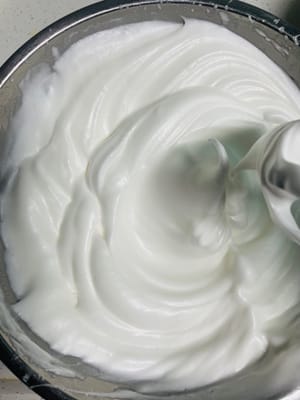 Zitronensaft und Speisestärke in eine Schüssel geben. Mit einem elektrischen Handrührgerät auf niedriger Stufe schaumig schlagen. Die erste Portion Zucker hinzufügen und auf mittlerer bis hoher Stufe weiterschlagen, bis der Schaum feiner wird. Die zweite Portion Zucker hinzufügen und weiterschlagen, bis klare Linien sichtbar sind. Die dritte Portion Zucker hinzufügen und auf niedriger Stufe schlagen, bis sich kurze, gerade Spitzen bilden.