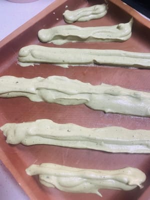 Heizen Sie den Backofen mindestens 10 Minuten lang auf 150 °C (300 °F) vor. Legen Sie eine 28 x 28 cm große Backform mit Backpapier aus.

Hinweis: Jetzt ist Ihr Geschick beim Spritzen von geraden Linien gefragt! Die Größe der Spritzbeutelöffnung und der Druck beim Aufspritzen des Teigs müssen für beide Farben gleich sein, sonst werden die Streifen krumm und bilden ein „S“! Schneiden Sie in jeden Spritzbeutel eine kleine Öffnung und spritzen Sie abwechselnd roten Hefereis- und Matcha-Teig in die Backform, um weihnachtliche Streifen zu gestalten (siehe Abbildung).

Heben Sie die Backform nach dem Aufspritzen an und lassen Sie sie zweimal vorsichtig aus etwa 10 cm Höhe fallen, um die Oberfläche zu glätten (es ist in Ordnung, wenn sich die Farben vermischen). Entfernen Sie größere Luftblasen und backen Sie den Kuchen anschließend 20 Minuten lang auf der mittleren Schiene des vorgeheizten Ofens bei 150 °C (300 °F).

Den gebackenen Kuchen sofort aus dem Ofen nehmen, auf ein Kuchengitter stürzen und, solange er noch warm ist, das Backpapier abziehen. Den Kuchen vollständig auskühlen lassen.