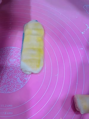 Deuxième étalage et façonnage. Prenez la pâte étalée et façonnée une première fois, aplatissez-la légèrement avec vos mains, puis roulez-la sur elle-même (sans la rouler d'avant en arrière), comme pour une pâte à l'huile. Retournez-la et roulez-la à nouveau, couvrez-la de film alimentaire et réservez. Essayez de l'aplatir légèrement au rouleau à pâtisserie avant de l'étaler. Cela permettra d'obtenir une pâte à l'huile plus homogène et une couleur plus uniforme. Ce deuxième étalage et façonnage sert à créer davantage de couches et à accentuer le feuilletage.