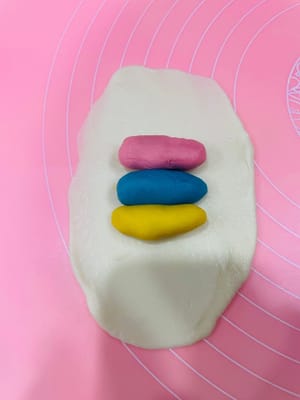 Enrobage de la pâte à base d’huile, premier étalage et repos

Déposez trois portions de 9 g de pâte à base d’huile (ou une portion de 27 g) au centre de la pâte à l’eau, appuyez légèrement avec la paume de la main, puis repliez-la sur elle-même de haut en bas et de gauche à droite. Retournez-la et aplatissez-la délicatement avec un rouleau à pâtisserie, puis tapotez-la avec la main pour uniformiser la pâte à base d’huile et obtenir une surface plus lisse et esthétique. Ensuite, comme pour l’étalage de la pâte à l’eau, roulez-la dans le sens de la longueur, en veillant à ne pas la rouler d’avant en arrière. Retournez-la à nouveau et roulez-la. Ce roulage permet de mieux distinguer les couches de pâte à l’eau et de pâte à base d’huile, ce qui donnera une texture feuilletée plus belle à la cuisson.

Après avoir enrobé toute la pâte à base d’huile avec la pâte à l’eau et l’avoir roulée, laissez reposer 15 minutes. Ce temps de repos est essentiel pour éviter que la pâte ne se déchire si vous la roulez sans cesse.