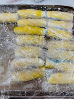 包油酥、第一次擀卷及松弛
将3个9g的油酥(或一个27克的油酥)放在油皮中间,稍微用手掌压一下,然后上下左右包起来,再反过来用擀面杖轻轻压平,用手拍扁,以便油酥更均匀更好看。然后像擀油皮那样,向上擀一下,下擀一下,左右各擀一下,千万不要来回擀,然后再反过来卷起来备用。卷起来是为了让油皮和油酥分层更明显,烤的时候起酥更漂亮。
全部油皮包油酥卷起来后,松弛15分钟。松弛是为了让面皮休息一下,不然一直擀容易破,这步不能省。