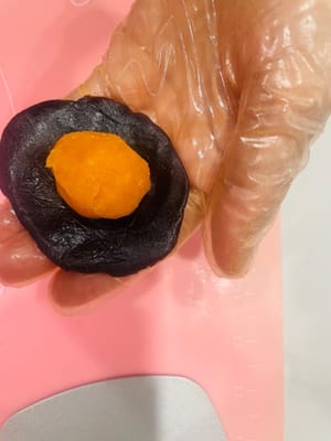 Garniture. Aplatissez légèrement la farce de pâte de haricots rouges, enveloppez-en la farce de porc effiloché et de jaune d’œuf, puis formez une boule. L’alternance de pâte de haricots rouges, de porc effiloché et de jaune d’œuf crée ainsi une texture en couches.