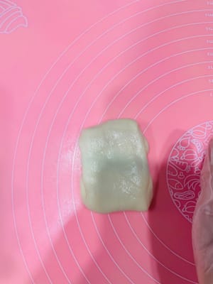 Enrobage de la pâte à base d’huile, premier étalage et repos

Déposez trois portions de 9 g de pâte à base d’huile (ou une portion de 27 g) au centre de la pâte à l’eau, appuyez légèrement avec la paume de la main, puis repliez-la sur elle-même de haut en bas et de gauche à droite. Retournez-la et aplatissez-la délicatement avec un rouleau à pâtisserie, puis tapotez-la avec la main pour uniformiser la pâte à base d’huile et obtenir une surface plus lisse et esthétique. Ensuite, comme pour l’étalage de la pâte à l’eau, roulez-la dans le sens de la longueur, en veillant à ne pas la rouler d’avant en arrière. Retournez-la à nouveau et roulez-la. Ce roulage permet de mieux distinguer les couches de pâte à l’eau et de pâte à base d’huile, ce qui donnera une texture feuilletée plus belle à la cuisson.

Après avoir enrobé toute la pâte à base d’huile avec la pâte à l’eau et l’avoir roulée, laissez reposer 15 minutes. Ce temps de repos est essentiel pour éviter que la pâte ne se déchire si vous la roulez sans cesse.