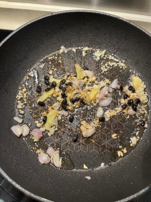 Après avoir senti un peu de parfum, versez les haricots noirs fermentés et continuez à faire sauter.