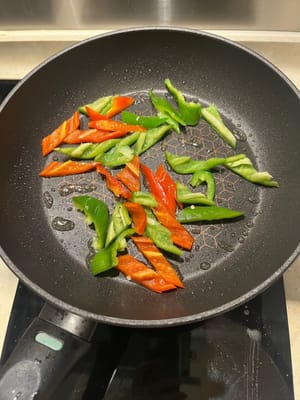 Ajoutez un peu de sel et faites frire les poivrons verts et rouges jusqu'à ce qu'ils soient cuits à 70 %.