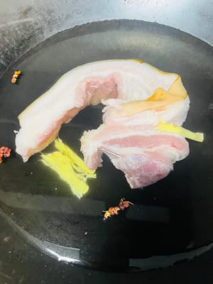 Enjuagar la panceta y ponerla en agua fría. Añadir jengibre, pimienta y vino de cocina y blanquearla. Retirar del fuego, lavar y escurrir.
