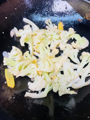 將肉剷出嚟，鍋裡留香料和油，倒椰菜花炒至斷生，加少許底鹽（乾鍋醬鹹，別加多）。注意！全程不加水，中小火炒，可蓋鍋蓋加速成熟。