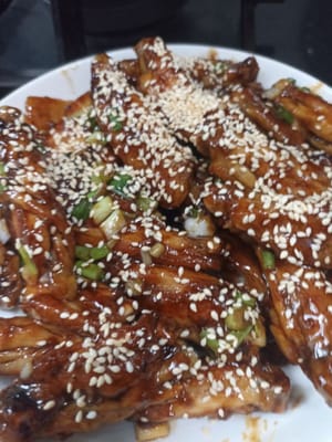 Soulevez les ailes de poulet puis placez-les sur une assiette et saupoudrez de graines de sésame grillées et les ailes de poulet teriyaki sont prêtes à être servies.