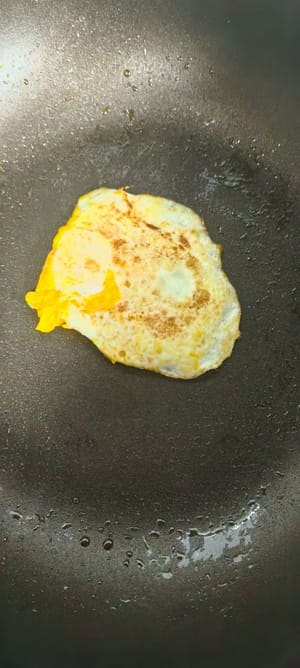 Spennellare una padella con un filo d'olio, friggere un uovo, quindi friggere alcune fette di prosciutto finché entrambi i lati non saranno leggermente dorati.