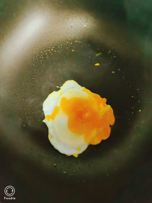 Spennellare una padella con un filo d'olio, friggere un uovo, quindi friggere alcune fette di prosciutto finché entrambi i lati non saranno leggermente dorati.