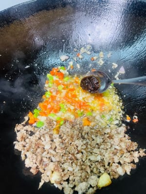 Zutaten anbraten: Zuerst das Hackfleisch an den Rand der Pfanne schieben, dann das Öl am Pfannenboden verwenden, um den gehackten Knoblauch, die Knoblauchpaste, die roten Chilischoten und die Schalotten anzubraten, bis sie duften.