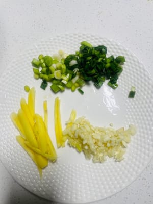 Zutaten: Ingwer in dünne Streifen schneiden, Knoblauchsprossen hacken, den weißen und grünen Teil des Knoblauchs trennen und Knoblauch fein hacken.