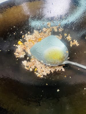 Für die Basisaromen anbraten: Öl in einer Pfanne bei schwacher Hitze erhitzen, zerdrückte Knoblauchzehen und Ingwerscheiben hinzufügen und anbraten, bis sie duften (für eine leichtere Konsistenz können Sie die Knoblauchzehen entfernen; ansonsten in der Pfanne lassen).

Hackfleisch hinzufügen und von beiden Seiten goldbraun anbraten, dabei das Fett auslassen. Einen kleinen Löffel weißen Pfeffer hinzufügen, dann einen Löffel Kochwein am Pfannenrand entlang träufeln und gleichmäßig braten.