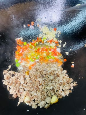 Zutaten anbraten: Zuerst das Hackfleisch an den Rand der Pfanne schieben, dann das Öl am Pfannenboden verwenden, um den gehackten Knoblauch, die Knoblauchpaste, die roten Chilischoten und die Schalotten anzubraten, bis sie duften.