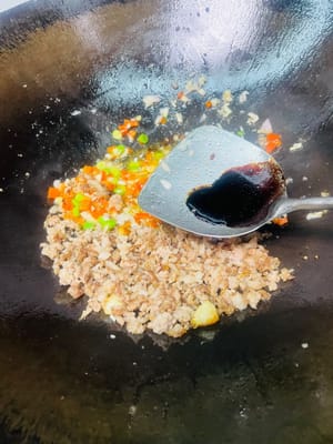 Anbraten, um das rote Öl freizusetzen: Einen Löffel Pixian-Chilibohnenpaste in die Mitte des Topfes geben, anbraten, bis das rote Öl austritt, dann gleichmäßig mit dem Hackfleisch anbraten und einen Löffel dunkle Sojasauce für die Farbe hinzufügen.