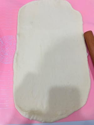 Menggilas adonan
Keluarkan adonan roti panggang besar dan giling menjadi lembaran tipis dan panjang, sekitar 20 cm lebar dan 30 cm panjang. Ketuk perlahan gelembung-gelembung besar saat Anda menggulung.