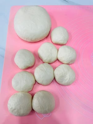 Degassing dan Membagi
Keluarkan adonan yang sudah mengembang dan uleni perlahan untuk mengeluarkan udara. Kemudian bagi adonan menjadi bola-bola kecil. Jika membuat roti kecil, masing-masing seberat 80-100 gram sudah cukup. Gulung adonan menjadi bola-bola, tutup dengan plastik wrap, dan diamkan selama 15 menit, sama seperti kita membiarkan adonan didiamkan.
Saya membuat loyang roti 450g, jadi adonan saya 480g.