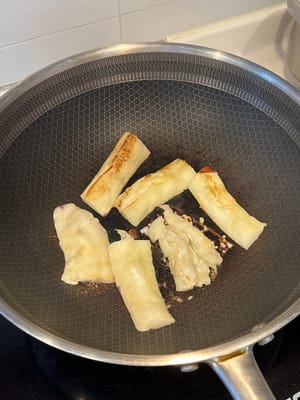 在加热的平底锅中倒入少量油，将茄子两面煎至略呈褐色。