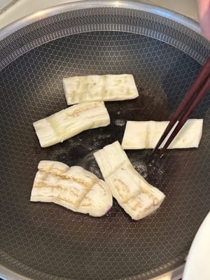 在加热的平底锅中倒入少量油，将茄子两面煎至略呈褐色。