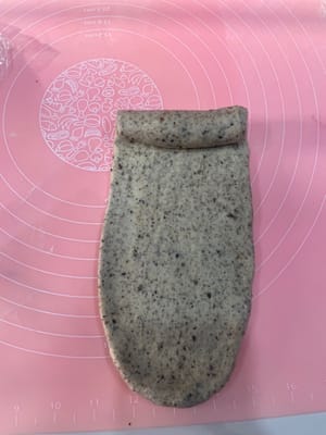 Take a rested dough ball, gently flatten it to release the air, roll it out into a long strip with a rolling pin, and roll it up; roll it out again, roll it up again, and place it vertically into a loaf pan.

Repeat this process for all three loaves, placing them one by one into the loaf pan.