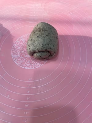 Take a rested dough ball, gently flatten it to release the air, roll it out into a long strip with a rolling pin, and roll it up; roll it out again, roll it up again, and place it vertically into a loaf pan.

Repeat this process for all three loaves, placing them one by one into the loaf pan.