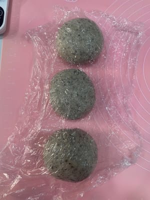 Take out the risen dough, deflate it, divide it into 3 equal portions, roll each portion into a ball, cover with plastic wrap, and let it rest for 10 minutes to allow the dough to breathe, making it easier to roll out later.