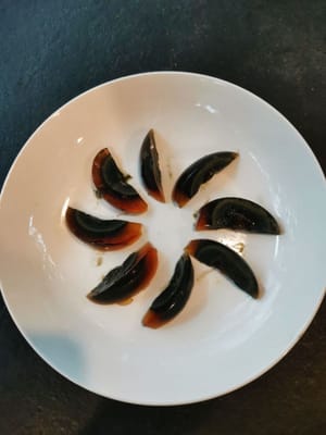 Épluchez les œufs noirs puis coupez-les en 8, puis disposez-les sur une assiette