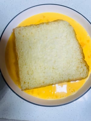 J’ai utilisé du pain grillé maison, coupé à l’épaisseur souhaitée ; si vous utilisez du pain grillé du commerce, deux tranches suffiront. Trempez le pain grillé dans le mélange d’œufs, en veillant à ce que toutes les faces soient bien enrobées et imbibées.