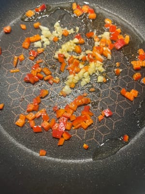 Aggiungere il peperone rosso, lo zenzero, i fagioli all'aglio e soffriggere insieme