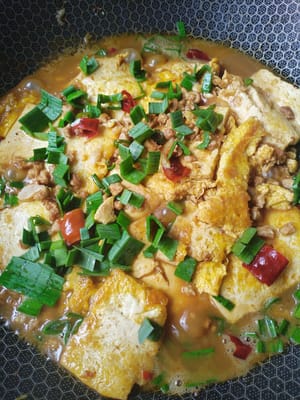 肉丁爆好加入煎煮的雞蛋豆腐翻炒10秒後，加一茶匙雞精，一茶匙鹽，一匙蠔油，倒入一匙調好生粉水翻炒10秒撒入蒜苗段起鍋裝盤。