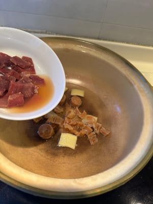 En una olla de barro limpia, colocar el jengibre, las vieiras secas remojadas con agua y el jamón chino como base.