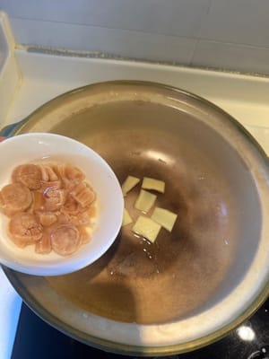 En una olla de barro limpia, colocar el jengibre, las vieiras secas remojadas con agua y el jamón chino como base.
