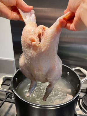 重覆浸水、提起這個動作三次。這樣做可使雞皮膨漲，稍後浸煮時雞皮不易破爛。