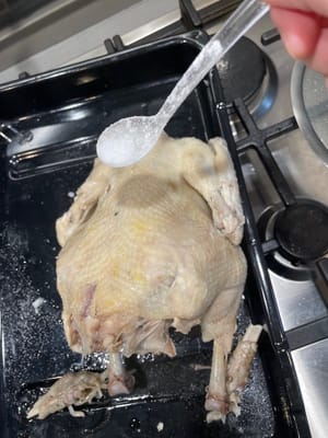 把雞隻取出，放在盤中，趁雞還熱在雞的表面及雞腔內塗抹鹽粒。