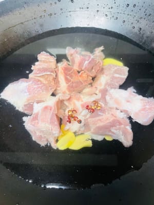 鍋に冷水、生姜のスライス、料理酒、胡椒、きれいに洗った豚骨を加えます。沸騰したら5分間煮ます。鍋から取り出して、きれいにし、脇に置いておきます。