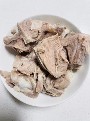 Add cold water, ginger slices, cooking wine, peppercorns, and cleaned pork bones to the pot. Boil for 5 minutes after the water boils. Remove from the pot, clean, and set aside.