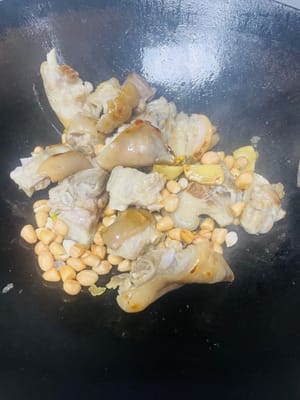 Add sliced ginger and pour cooking wine from the side of the pot to stimulate the aroma. Then add the soaked peanuts and stir-fry evenly. Be careful not to burn them.